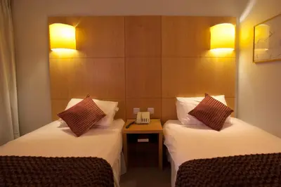 a hotel room with two beds and a night stand at Britannia Hotel Bolton in Bolton