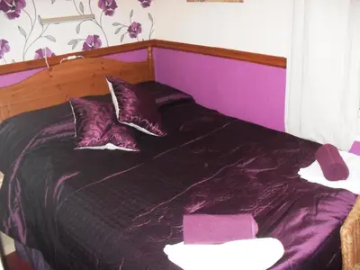 a purple bed with purple sheets and pillows at Bradleys Hotel in Blackpool