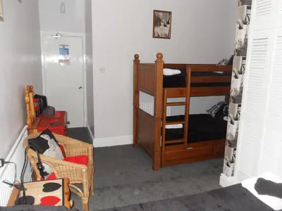 a small room with a bunk bed and a chair at Bradleys Hotel in Blackpool