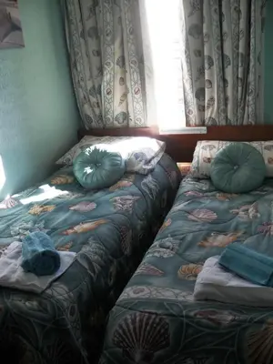 a bedroom with two beds with pillows and a window at Bradleys Hotel in Blackpool
