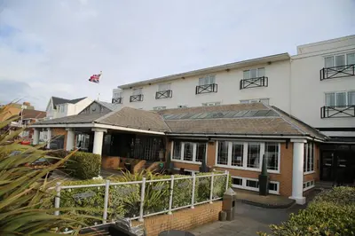 a large white building with a fence in front of it at Inn On The Prom At The Fernlea Hotel in Lytham St Annes