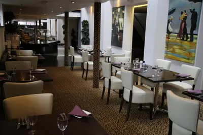 a dining room with tables and white chairs at Inn On The Prom At The Fernlea Hotel in Lytham St Annes