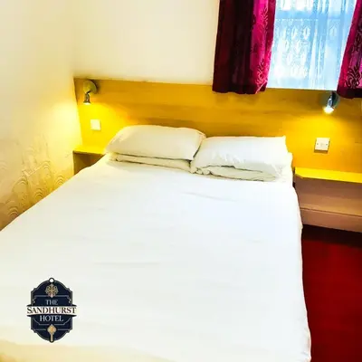 a bed with white sheets and pillows in a room at The Sandhurst Hotel in Blackpool