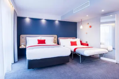 a bedroom with two beds and a blue wall at Holiday Inn Express - Wigan by IHG in Wigan
