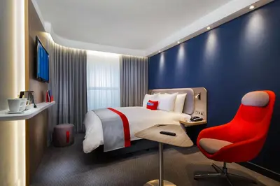 a hotel room with a bed and a red chair at Holiday Inn Express - Wigan by IHG in Wigan