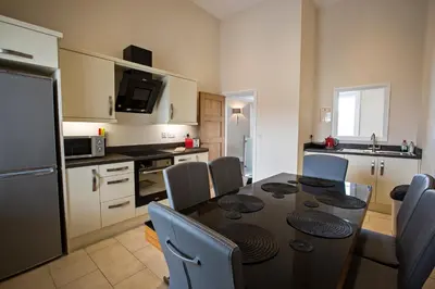 a kitchen with a black table and chairs and a kitchen with a table at Cider House in Ulverston