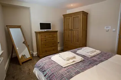 a bedroom with a bed with a dresser and a mirror at Cider House in Ulverston