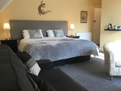 a bedroom with a large bed and a couch at Elton Guest House in Grange Over Sands