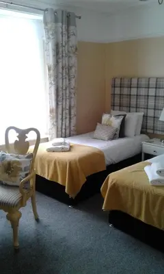 a bedroom with two beds and a couch and a window at Elton Guest House in Grange Over Sands