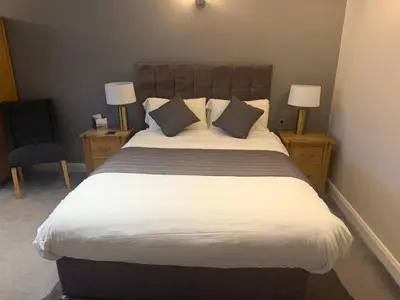 a bedroom with a large bed with two lamps and a chair at Charnock Farm in Leyland