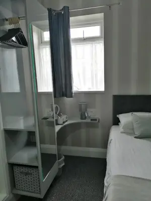 a bedroom with a mirror and a bed and a window at Balmoral in Morecambe