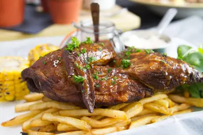 a plate of food with a piece of meat and french fries at Dalmeny Hotel in Lytham St Annes