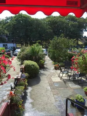 a garden with chairs and flowers and a red umbrella at The Fairmile in Lytham St Annes