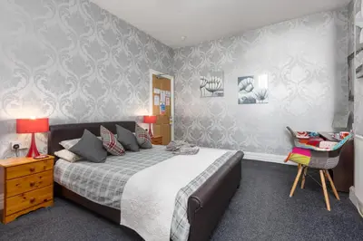 a bedroom with a bed and a table and a chair at The Fairmile in Lytham St Annes