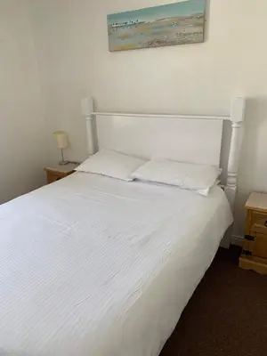 a white bed with two pillows and a picture on the wall at Delamere holiday flat in Blackpool
