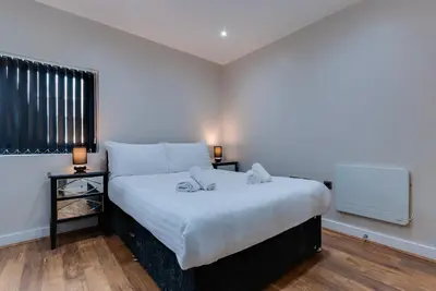 a bedroom with a white bed with two night stands at The Print Works Apartments in Liverpool