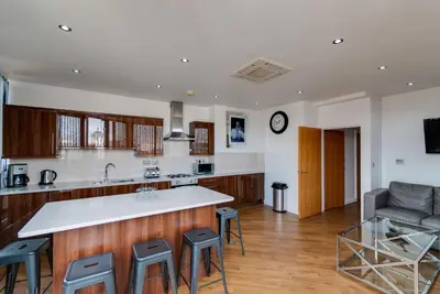 a kitchen with a counter and stools in a room at The Print Works Apartments in Liverpool