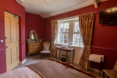 a red bedroom with a bed and a window at The Red Pump Inn in Clitheroe