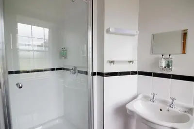 a white bathroom with a shower and a sink at The Red Pump Inn in Clitheroe