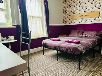 a bedroom with a bed with pink pillows on it at The Avon in Blackpool