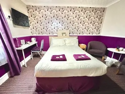 a bedroom with a large bed and a purple wall at The Avon in Blackpool