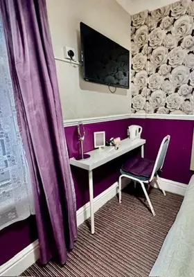 a purple room with a desk and a purple curtain at The Avon in Blackpool