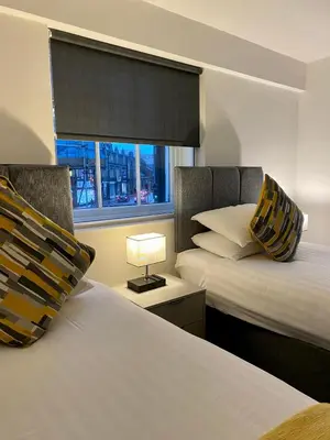 two beds in a room with a window and a lamp at Crows Hotel in Lancaster