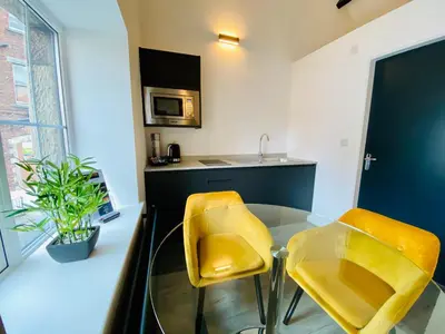 a kitchen with a glass table and two yellow chairs at Crows Hotel in Lancaster