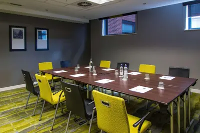 a conference room with a wooden table and yellow chairs at Hampton By Hilton Liverpool City Centre in Liverpool