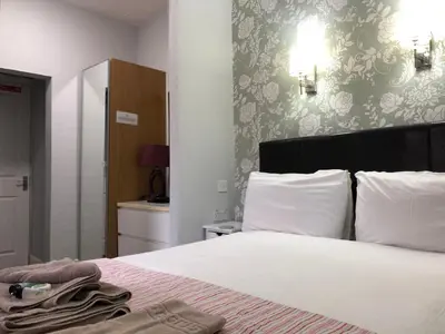 a bedroom with a bed with white sheets and a wall at Windsor Park Hotel in Blackpool