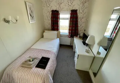 a small bedroom with two beds and a mirror at Windsor Park Hotel in Blackpool