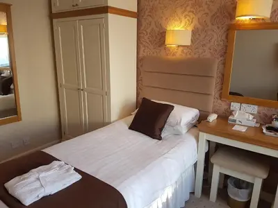 a small hotel room with a bed and a desk at Bedford Hotel in Lytham St Annes