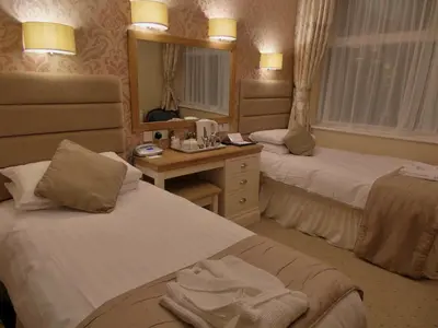 a hotel room with two beds and a desk at Bedford Hotel in Lytham St Annes