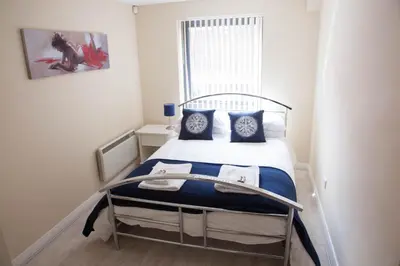 a small bedroom with a bed with blue and white pillows at City Centre Luxury Holiday Apartment in Liverpool