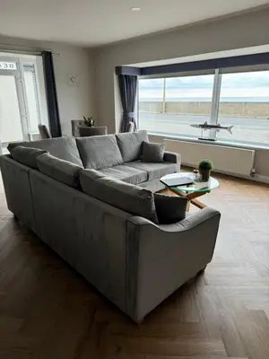 a large couch in a living room with a large window at Beach House Apartment on ground floor with sea view - pet friendly in Cleveleys