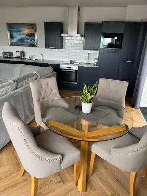a living room with a table and chairs and a kitchen at Beach House Apartment on ground floor with sea view - pet friendly in Cleveleys