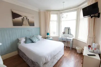 a bedroom with a white bed and a desk and windows at The Osprey Hotel in Blackpool
