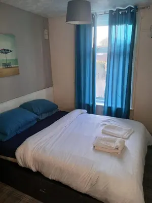 a bedroom with two beds and a window with blue curtains at The Osprey Hotel in Blackpool