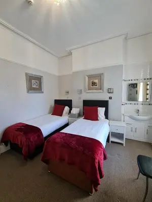 two beds in a hotel room with a sink at Clifton Villa - Southport in Southport