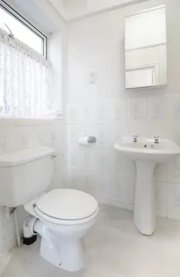 a white bathroom with a toilet and a sink at Clifton Villa - Southport in Southport