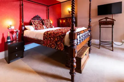 a bedroom with a four poster bed with red walls at The Royal Station Hotel in Carnforth