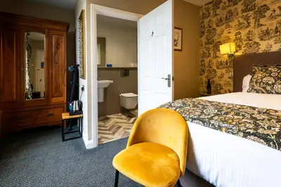 a bedroom with a bed and a yellow chair at The Royal Station Hotel in Carnforth