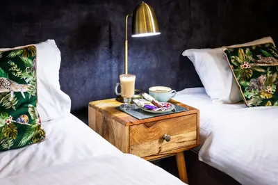 a room with two beds and a nightstand with a lamp at The Royal Station Hotel in Carnforth