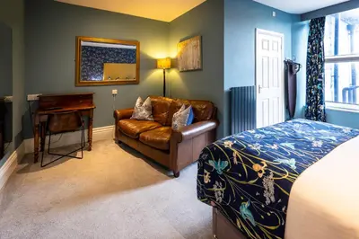 a bedroom with a couch and a bed and a desk at The Royal Station Hotel in Carnforth