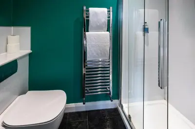 a green bathroom with a toilet and a shower at The Royal Station Hotel in Carnforth