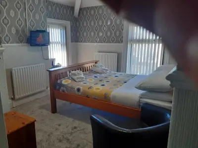 a bedroom with a bed and a chair in it at Wellington Hotel in Blackpool