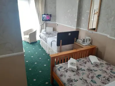 a bedroom with two beds and a desk with a laptop at Wellington Hotel in Blackpool