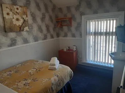 a bedroom with a bed and a window with flowers at Wellington Hotel in Blackpool