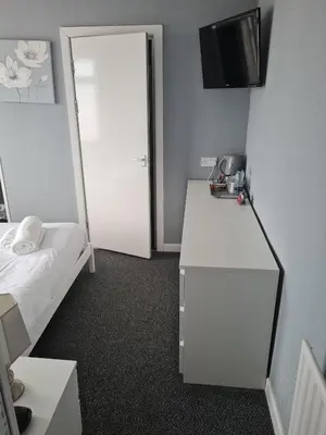 a bedroom with a bed and a mirror and a dresser at Queens Plaza Hotel in Blackpool