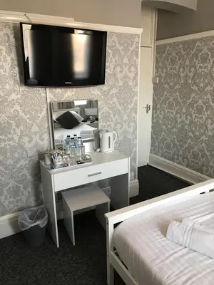 a hotel room with a bed and a desk with a mirror at Queens Plaza Hotel in Blackpool